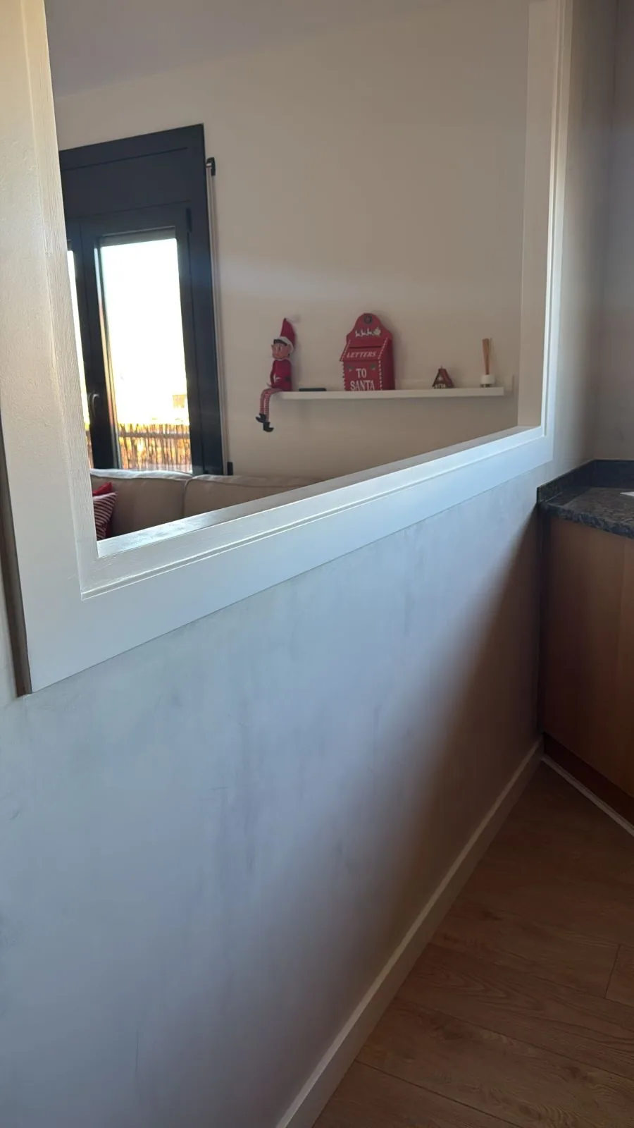 Pared de cocina revestida con microcemento gris claro junto a una ventana interior